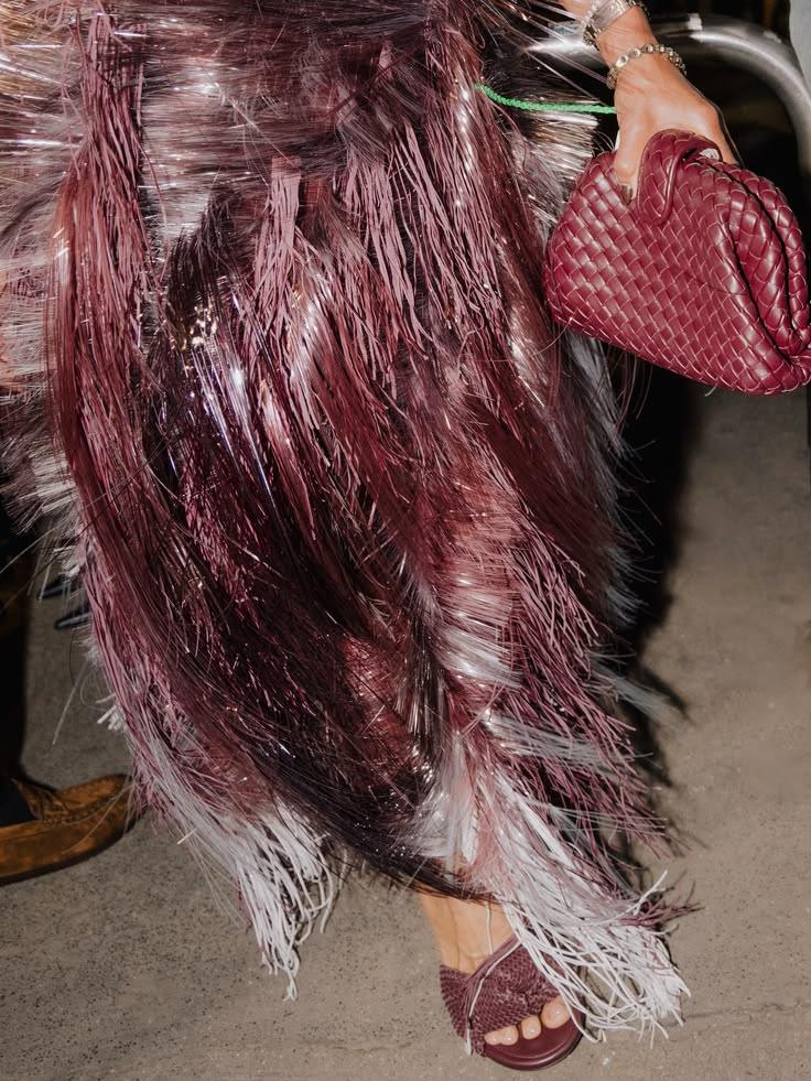 A fringed skirt and a woven red bag