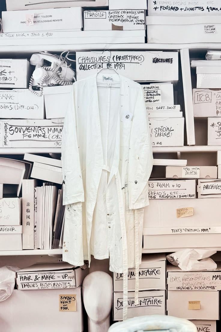 Archive shelves of labelled boxes and a white robe